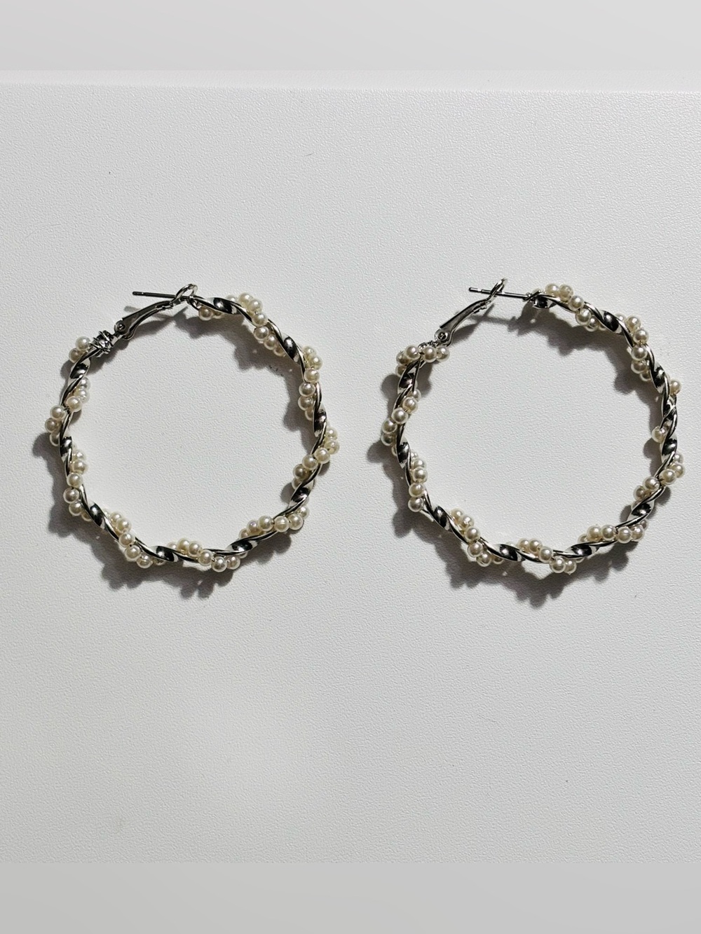 Silver-tone twisted hoop pierced earrings wrapped with petite faux pearls.